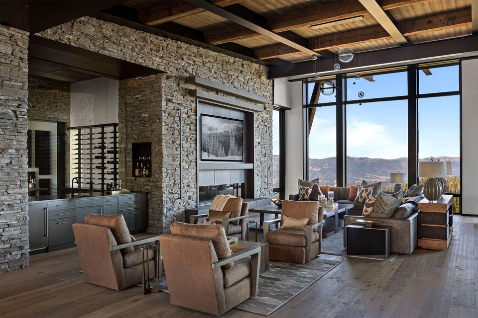 Private advisory interior of stone, timber and steel with large windows opening to a mountain view.